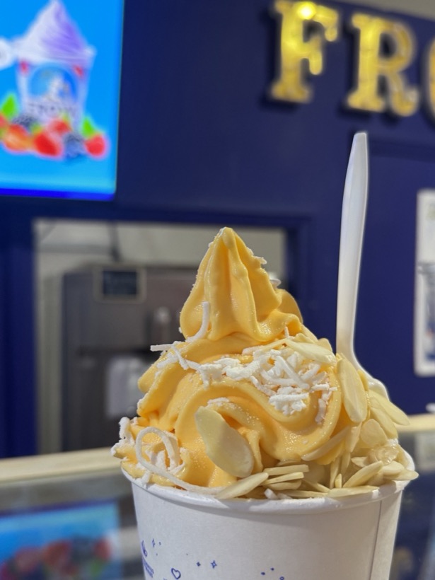 Vaso de yogurt griego de mango con coco rallado y almendra